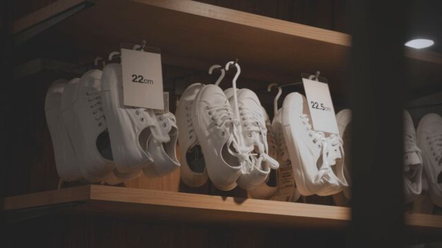 White sneakers elegantly displayed in a modern shop interior, showcasing minimalistic design on wooden shelves.