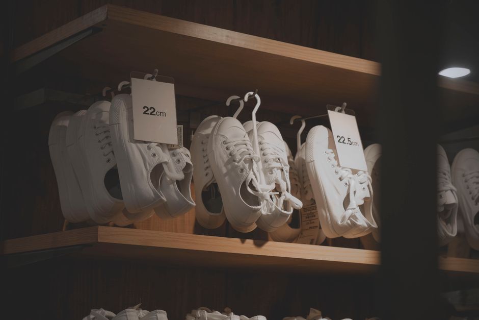 White sneakers elegantly displayed in a modern shop interior, showcasing minimalistic design on wooden shelves.